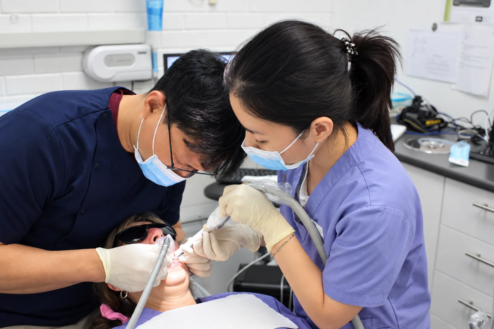 Dr John Paul Lee treating a patient with a dental assistant supporting chairside