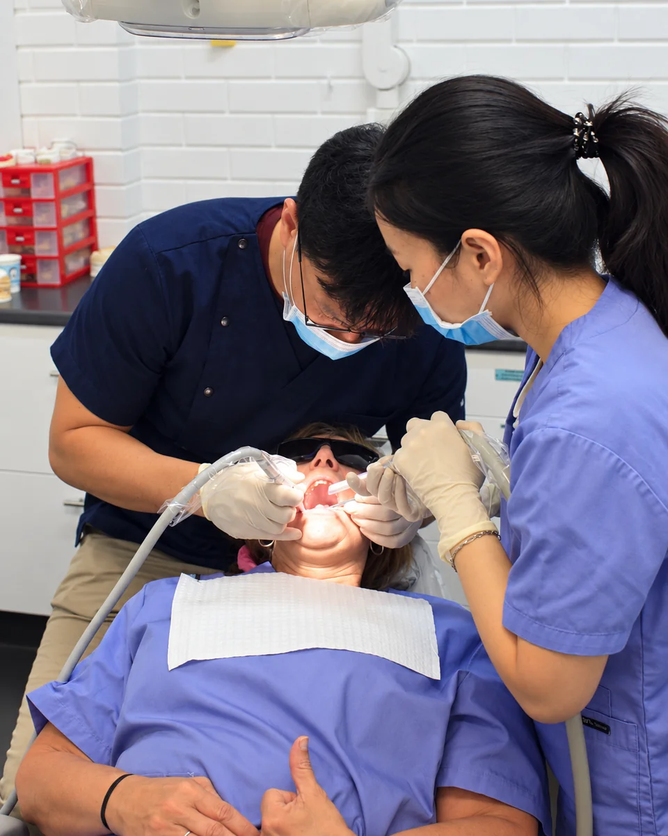 Dr John Paul Lee and a dental assistant treating a patient at New'Gen Dental Surgery